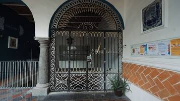 A gated entrance with decorative ironwork, a potted plant, and a wall with a bulletin board.