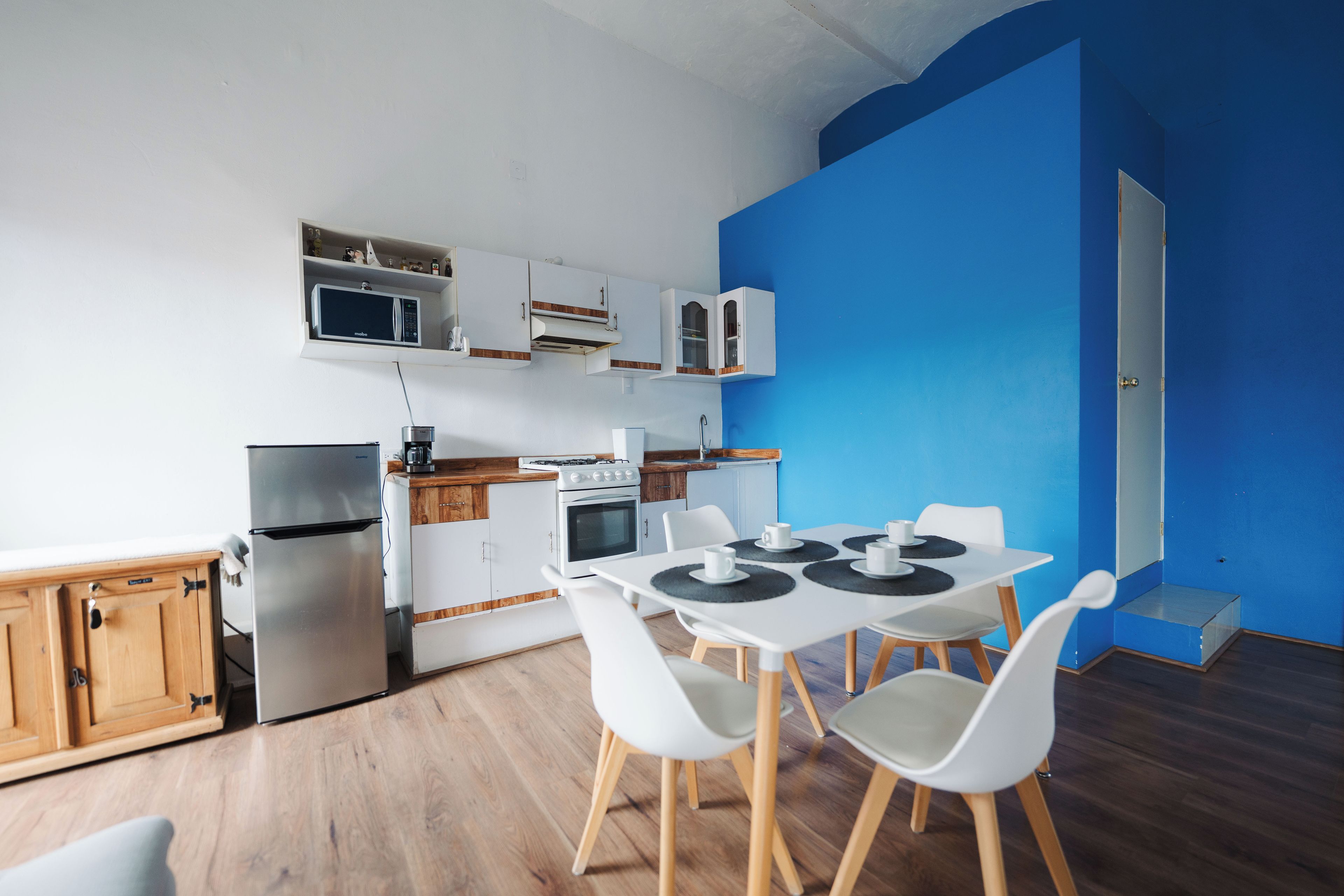 Cozinha moderna com armários brancos, micro-ondas, fogão e área de refeições com mesa e cadeiras.