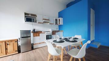 Cozinha moderna com armários brancos, micro-ondas, fogão e área de refeições com mesa e cadeiras.