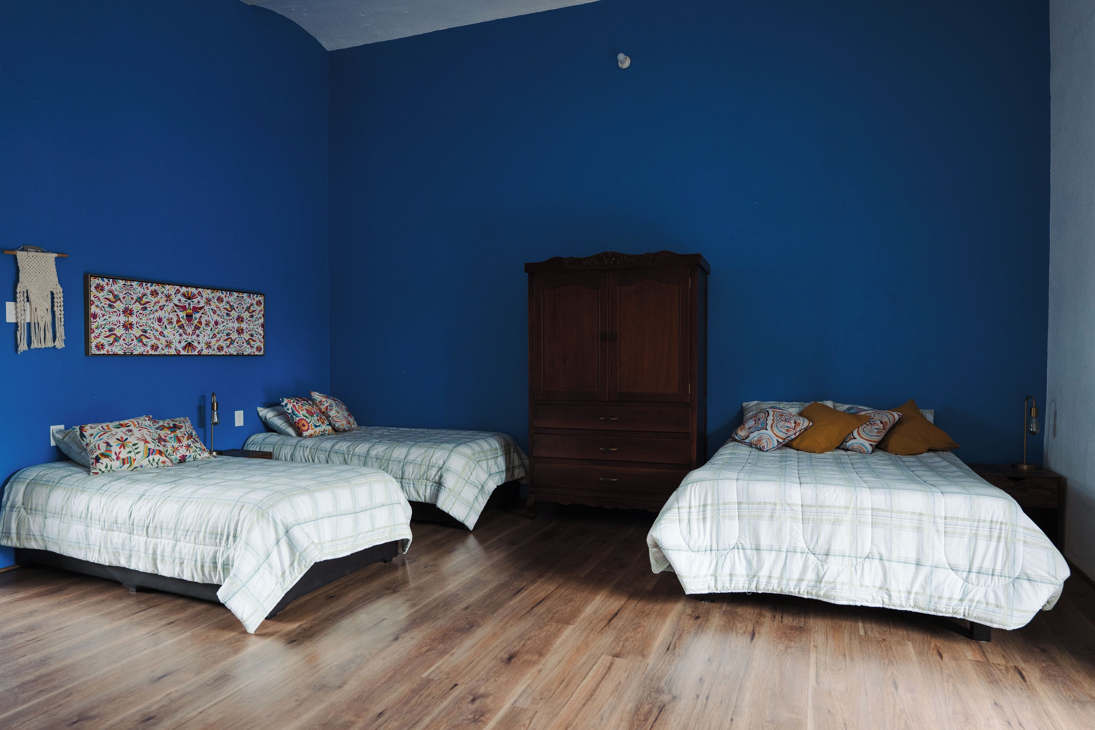 Une chambre avec deux lits, une armoire en bois et une tapisserie accrochée au mur.