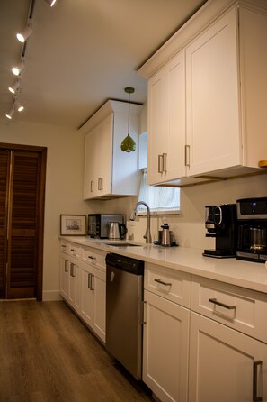 A modern kitchen with white cabinetry, stainless steel appliances, and a wooden floor. - Beautiful 3BR Home Near Dallas Perfect for Families & Groups (Garland)