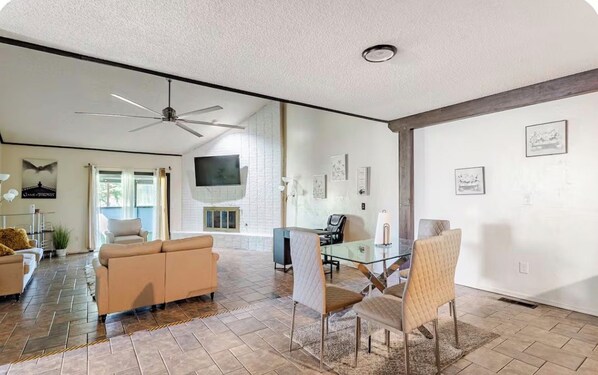 A spacious living area with a ceiling fan, a glass dining table, and a sofa.