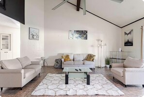 A modern living room with a sofa set, a glass coffee table, and a white shag rug.