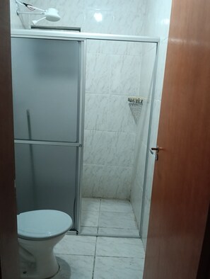 Un baño con inodoro, cabina de ducha y lavabo.
