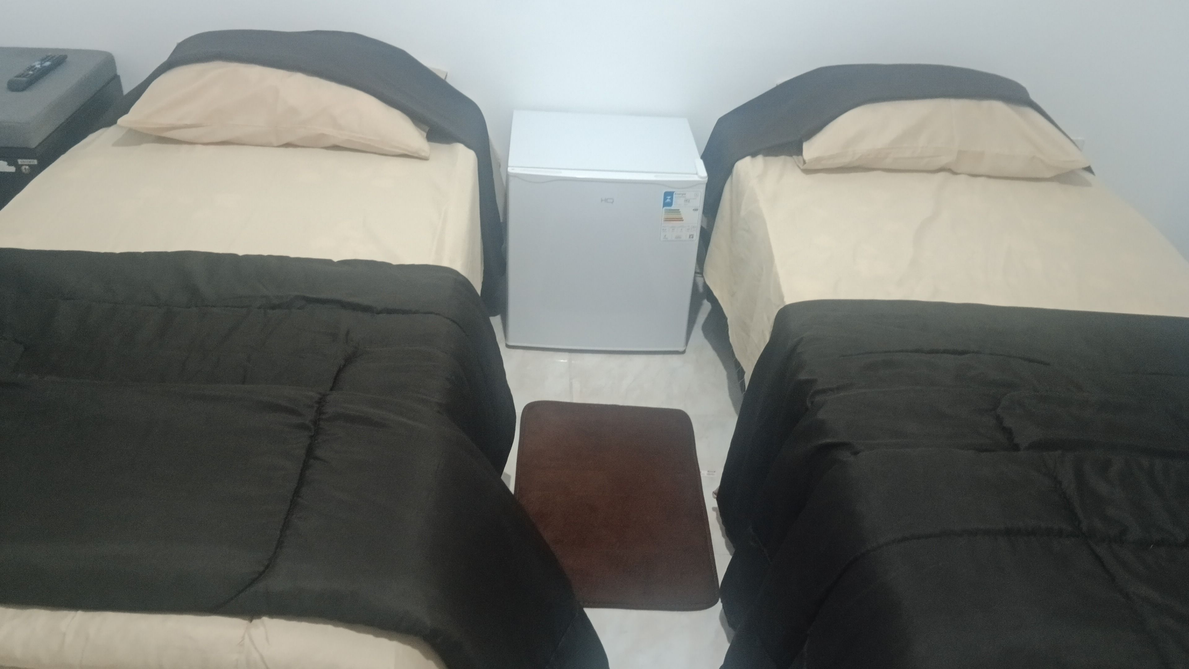 Ett rum med två sängar, ett litet bord och en vit apparat i mitten.