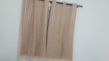 Un dormitorio con dos camas, una mesita de noche y una ventana con cortinas.