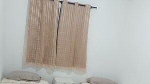 Quarto pequeno e limpo, com duas camas de solteiro, mesa de cabeceira e um pequeno armário.
