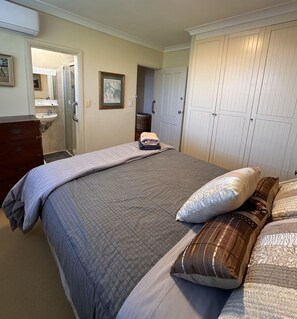 Une chambre à coucher avec un lit, des oreillers, une commode, un miroir et une armoire.