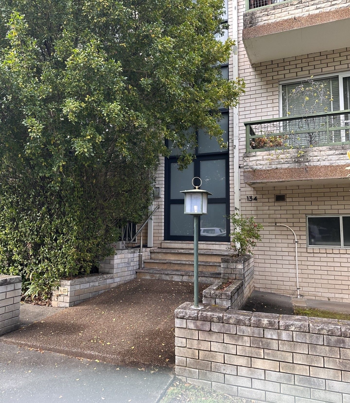A residential building with a brick facade, a visible window, and a metal railing on the balcony.