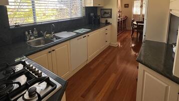 Une cuisine équipée d’une cuisinière à gaz, d’un évier et d’un plancher en bois.
