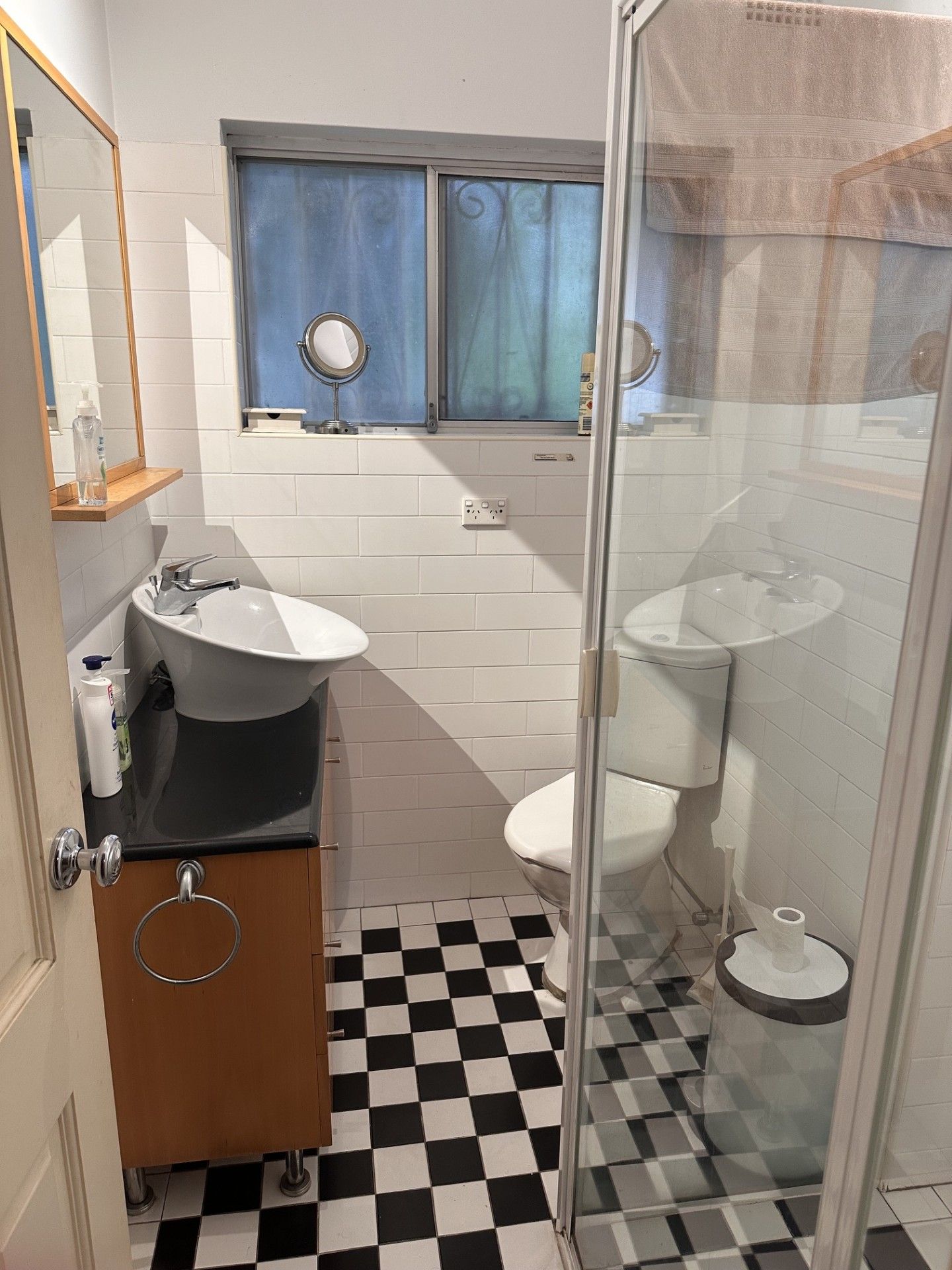 Une salle de bain avec un carrelage à motifs géométriques, une douche en verre, un lavabo, des toilettes et un miroir.