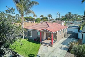 A residential house with a red-tiled roof, a front porch, and a well-maintained lawn. - Spacious 4-bedroom house in nice Long Beach with AC (Long Beach)