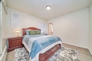 A bedroom with a bed, nightstand, and wall-mounted light fixture. - Spacious 4-bedroom house in nice Long Beach with AC (Long Beach)