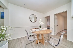 A modern dining area with a round wooden table, clear glass chairs, and a white orchid centerpiece. - Spacious 4-bedroom house in nice Long Beach with AC (Long Beach)