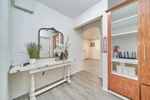 A hallway with a white console table, a mirror, and a wooden cabinet with shelves. - Spacious 4-bedroom house in nice Long Beach with AC (Long Beach)
