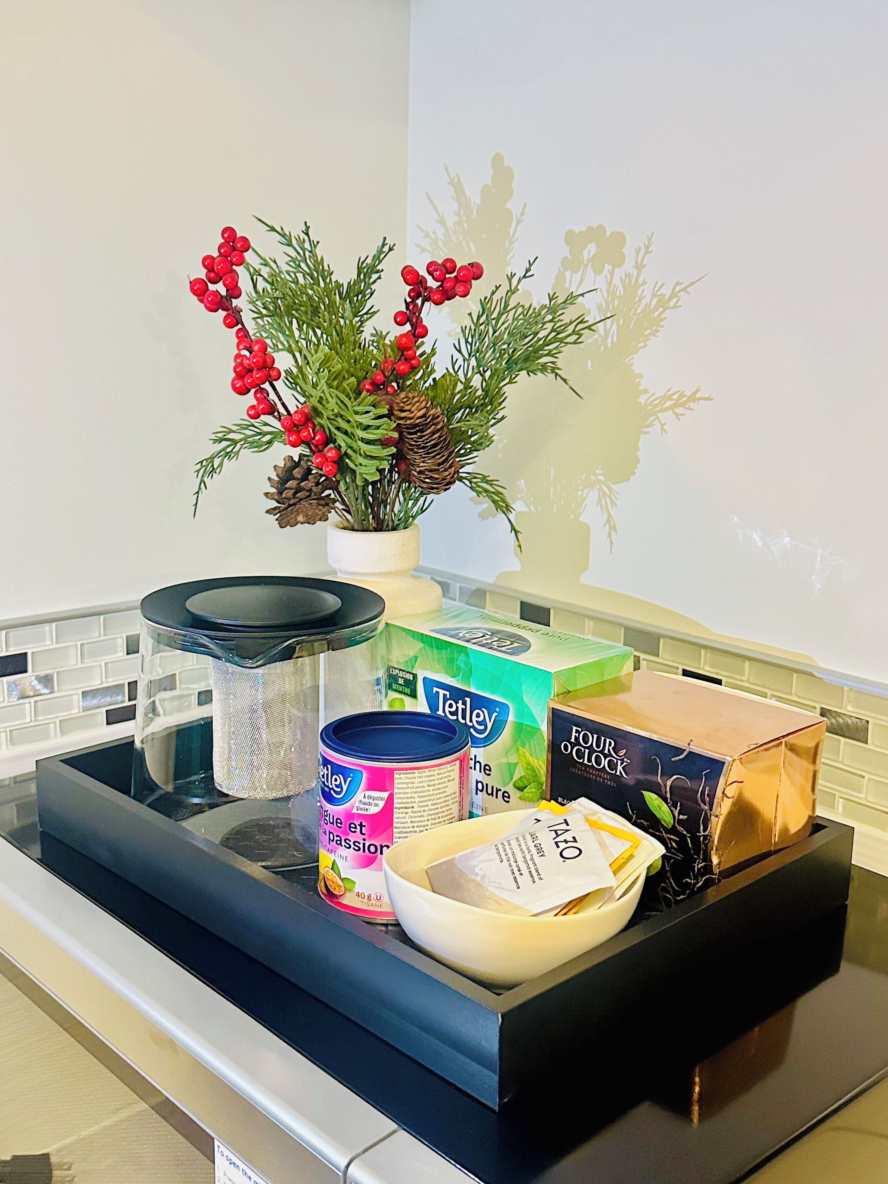 Een keukenblad met een bloempot, een koffiezetapparaat, een kom en verschillende soorten eten.