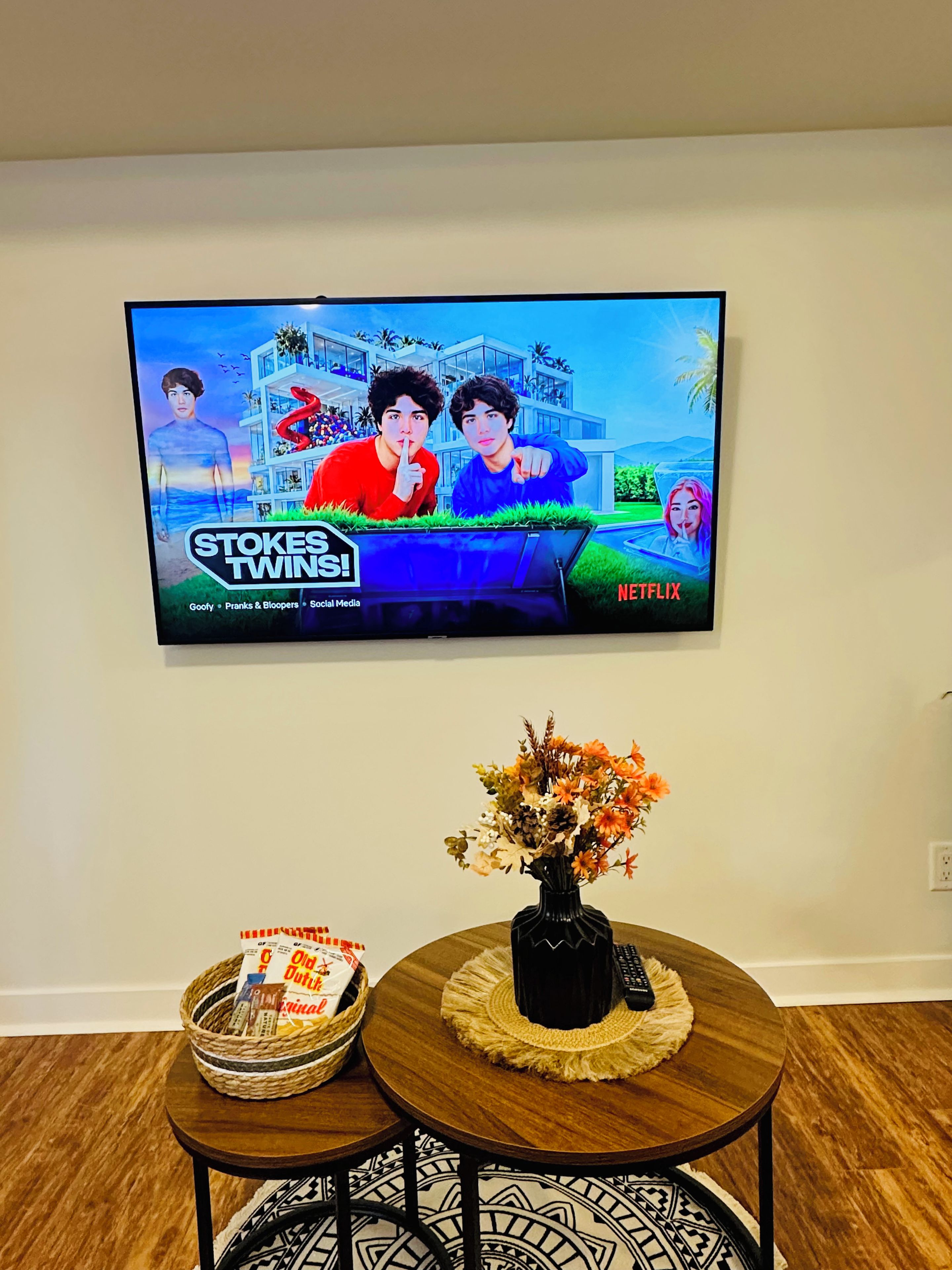 A television mounted on a wall displaying the Netflix series 'Stokes Twins.'