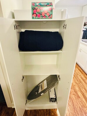 A white cabinet with a box of fruit-flavored yogurt on top, a dark-colored item on the middle shelf, and a protractor on the bottom shelf.