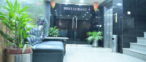 A modern lobby with a seating area, a staircase, and a restaurant entrance.