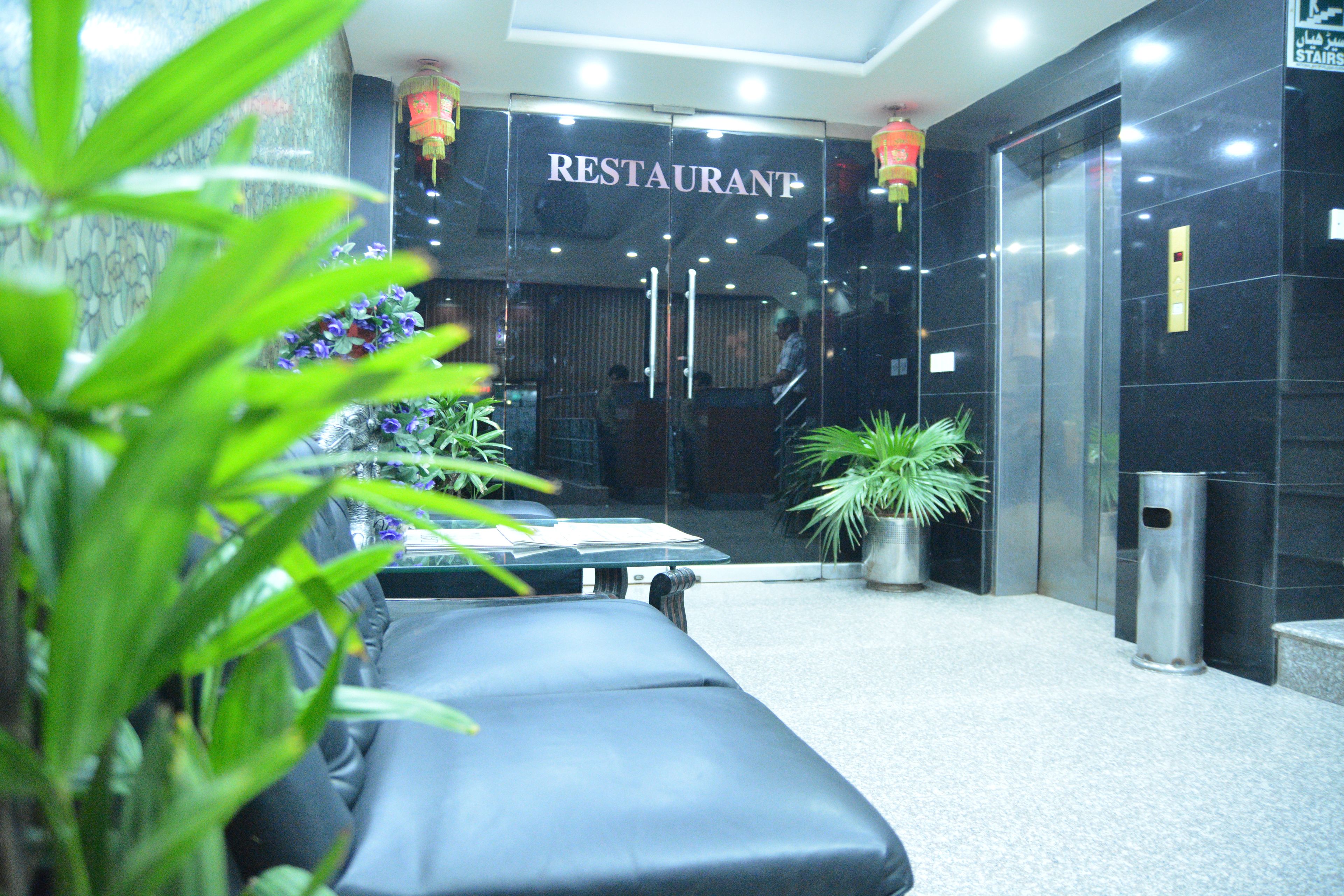 Un restaurante con un letrero sobre la entrada, una recepción y un área de estar con un banco.