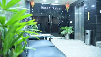 Un restaurant avec une enseigne au-dessus de l’entrée, un comptoir d’accueil et un espace où sont disposés des sièges, dont un banc.