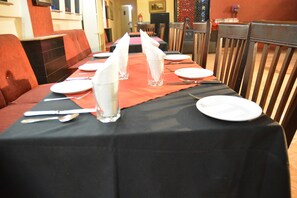 A dining table set with white plates, silverware, and clear glasses, with a red table runner. - Luxury One Hotel Lahore (Lahore)