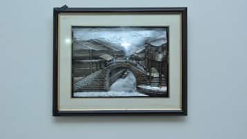 Une œuvre d’art encadrée représentant un paysage enneigé avec un pont et des bâtiments.