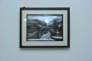 A framed artwork depicting a snowy scene with a bridge and buildings. - Luxury One Hotel Lahore (Lahore)