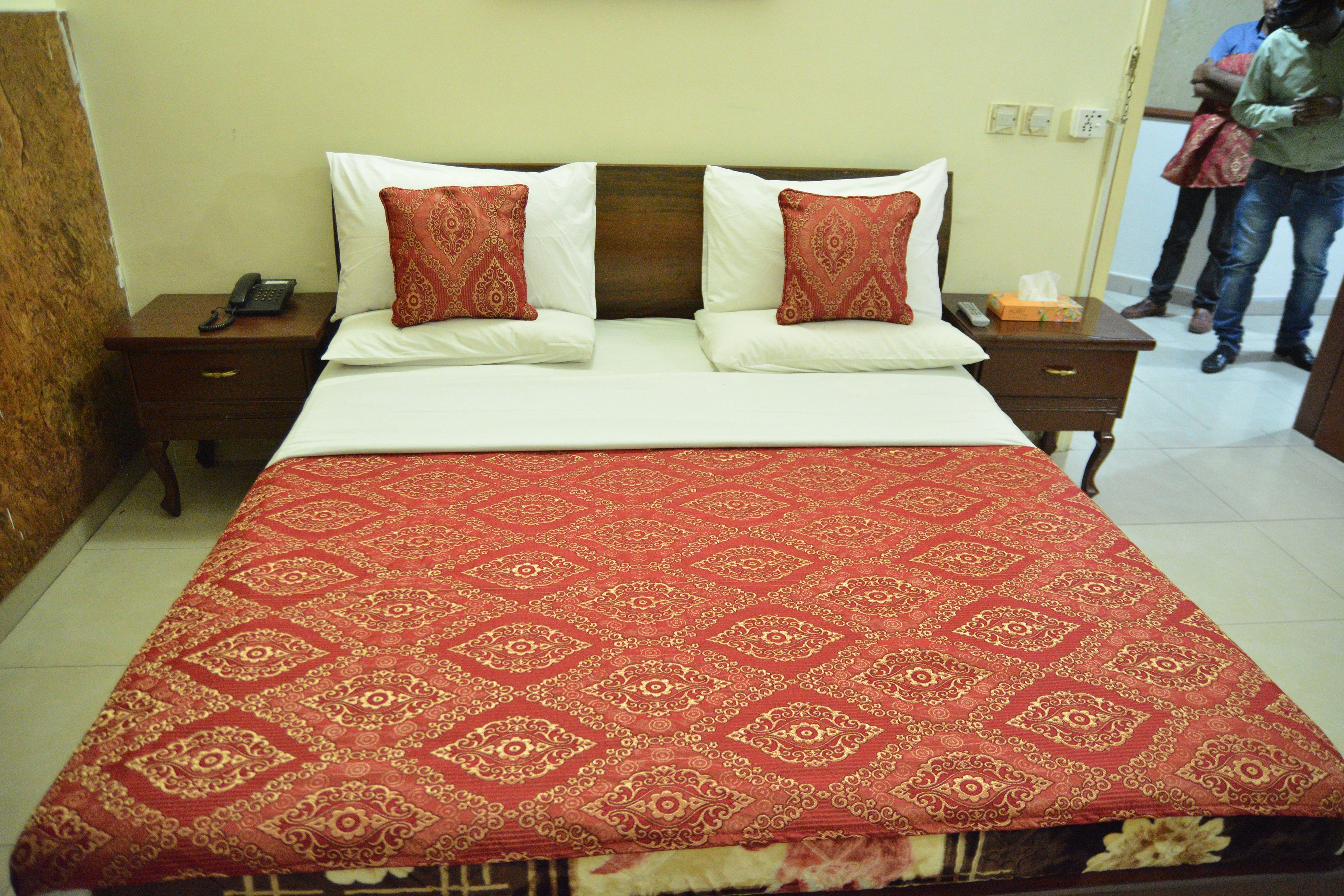 A hotel room with a bed, two bedside tables, a telephone, and a nightstand.