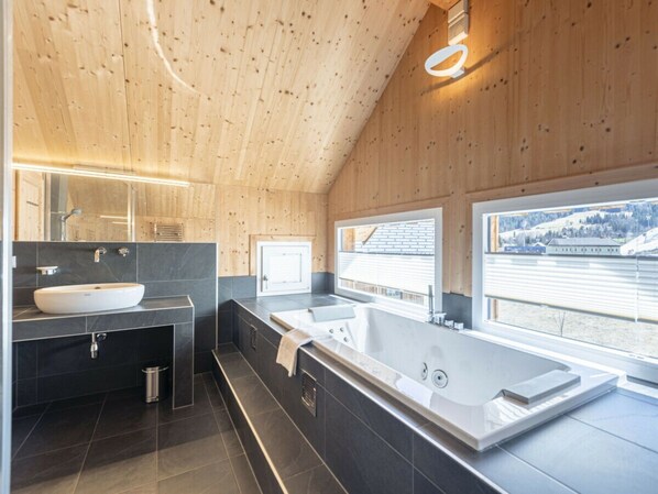 A modern bathroom with a large bathtub, a double sink, and a mirror. - One-bedroom Cabin (Sankt Georgen am Kreischberg)