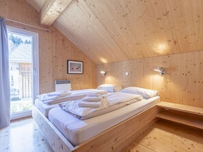Une chambre à coucher aux murs lambrissés, avec un lit, deux lampes de chevet et un tableau encadré accroché au mur.