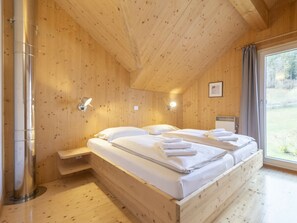 A wooden cabin bedroom with a bed, bedside tables, and a window. - One-bedroom Cabin (Sankt Georgen am Kreischberg)