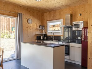 A modern kitchen with wooden walls, a central island, and built-in appliances. - One-bedroom Cabin (Sankt Georgen am Kreischberg)