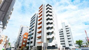 Un edificio de varios pisos con un diseño arquitectónico moderno, que cuenta con balcones en cada nivel.