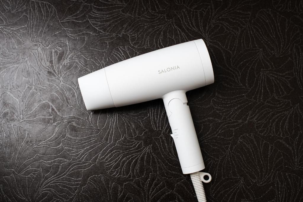 A white hairdryer with the brand name 'SALONIA' on a dark, textured surface.