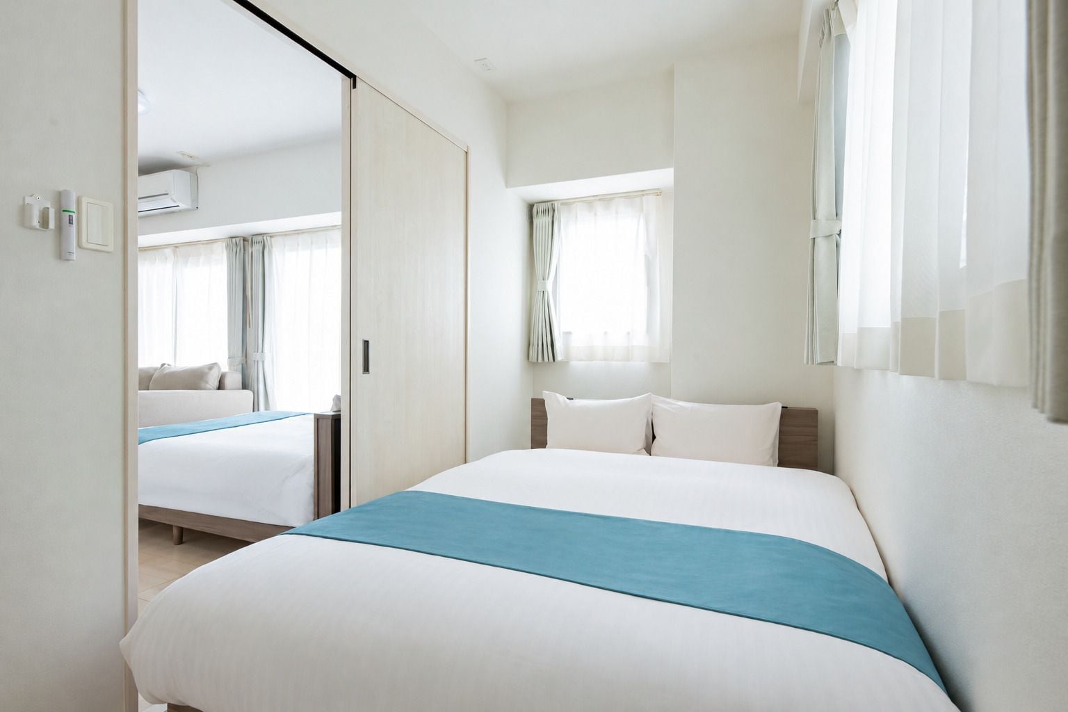 A hotel room with a large bed, a bedside table, a wardrobe, and a window with curtains.