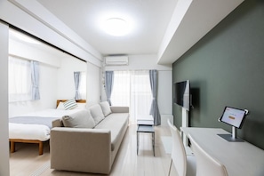 A modern hotel room with a sofa, a bed, a TV, and a desk with a computer. - Presence Hakata (Fukuoka City Hakata-ku Chiyo)