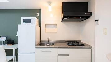A compact kitchen with a microwave, stove, sink, and a small countertop area.