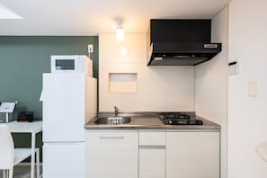 A compact kitchen with a microwave, stove, sink, and a small countertop area. - Presence Hakata (Fukuoka City Hakata-ku Chiyo)