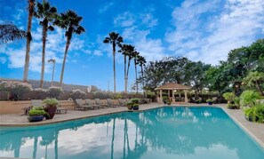 A swimming pool with lounge chairs, palm trees, and a gazebo. - By GALLERIA near NGR King bedroom Condo. Library, Swimming Pool, Gym, Garden BBQ (Houston)
