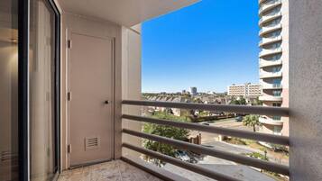 A balcony with a clear view of a cityscape, a door, and a window with blinds.