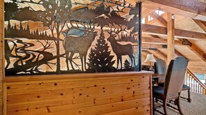 A wooden cabin interior with a mural of wildlife, a dining area with a table and chairs, and a staircase leading to the upper level. - Dancing Bear Lodge, Pine AZ; Luxury Cabin with Views, Spa & Outdoor living area (Pine)