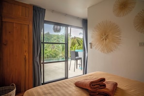 A room with a bed, a view of a pool and greenery, and a wooden wardrobe. - 3 Bed Jungle View in Bang Por (KBR64) (Koh Samui)