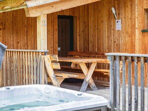 A wooden cabin with a hot tub, wooden deck, and a bench. - One-bedroom Cabin (Sankt Georgen am Kreischberg)
