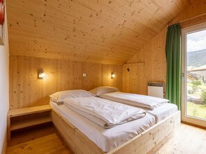 A wooden cabin room with two beds, a bench, and a window with a view of the outdoors. - One-bedroom Cabin (Sankt Georgen am Kreischberg)