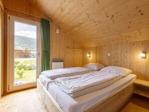 A wooden cabin room with a bed, a window, and a view of the outdoors. - One-bedroom Cabin (Sankt Georgen am Kreischberg)