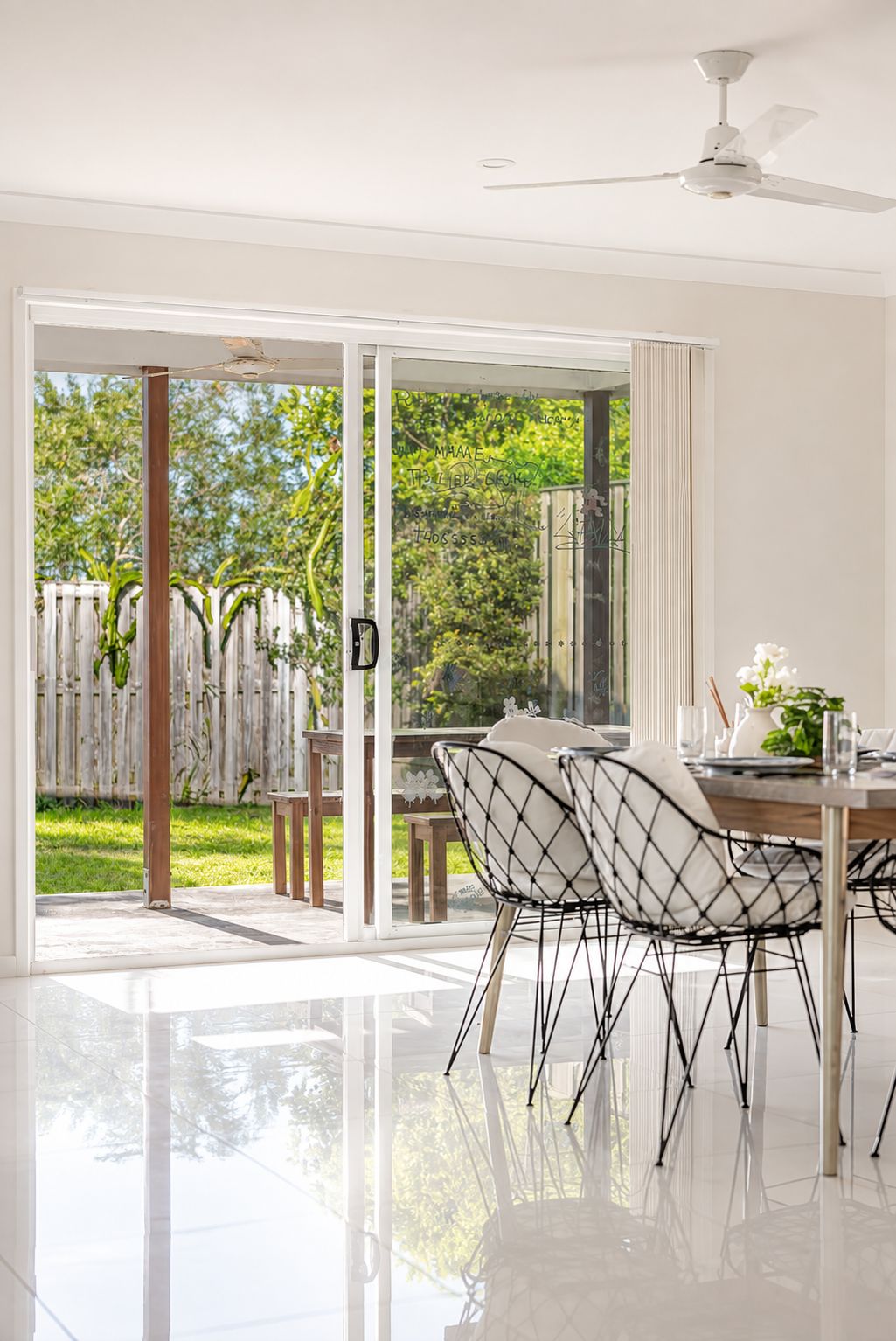 Ein moderner Essbereich mit Glastür zum Garten, Deckenventilator und Tisch für zwei Personen.