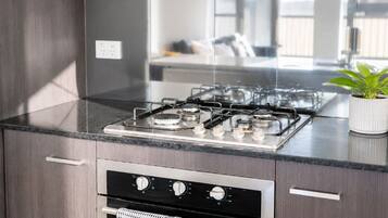 Une cuisine moderne équipée d’une cuisinière et d’un four en acier inoxydable, ainsi que d’une plante en pot posée sur le plan de travail.