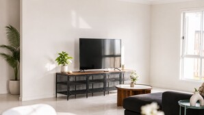 Un saló modern amb un televisor de pantalla plana, un sofà, una taula de centre i una planta en test.