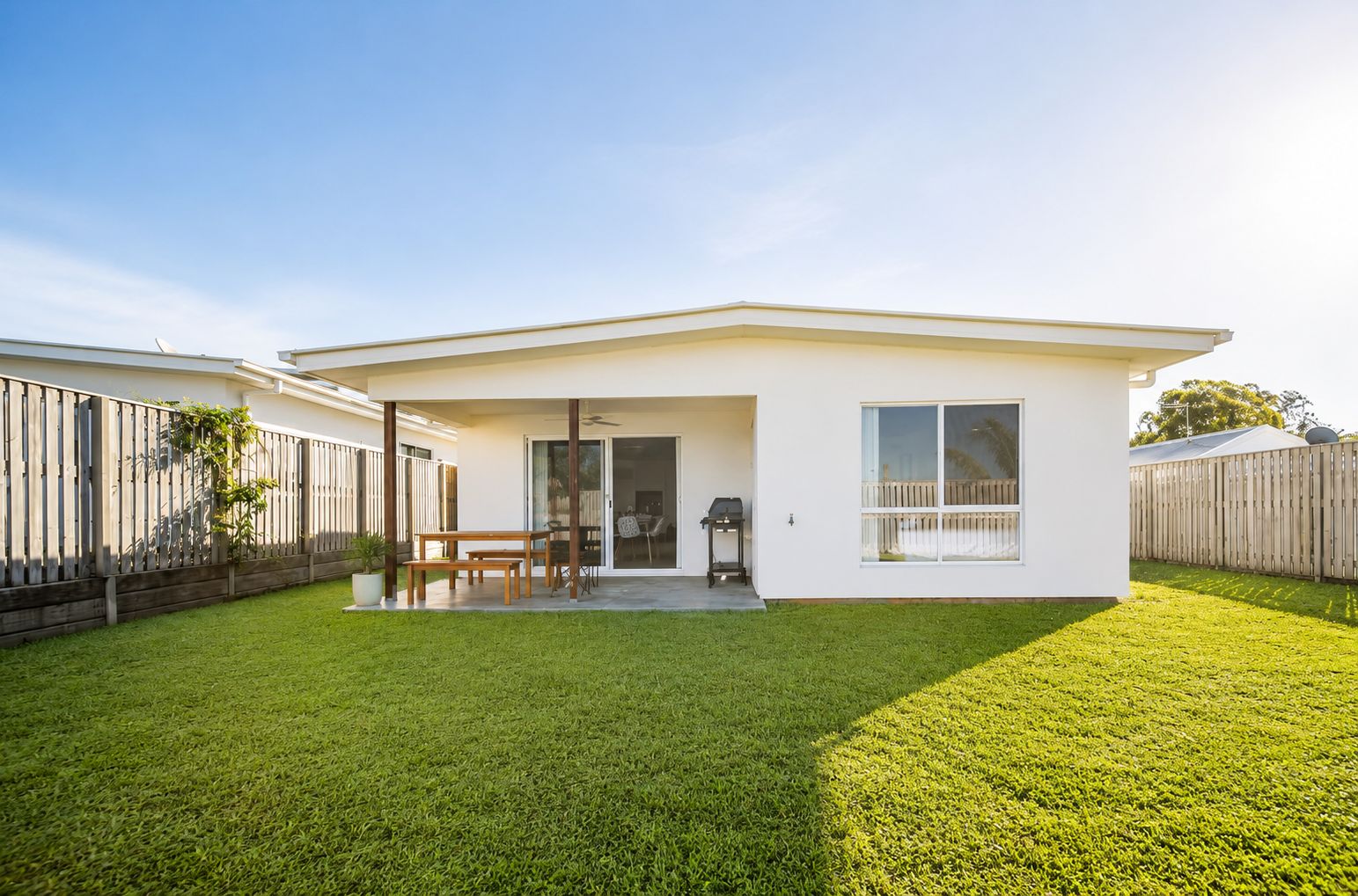 A modern single-story house with a covered patio, a sliding glass door, and a fenced backyard.
